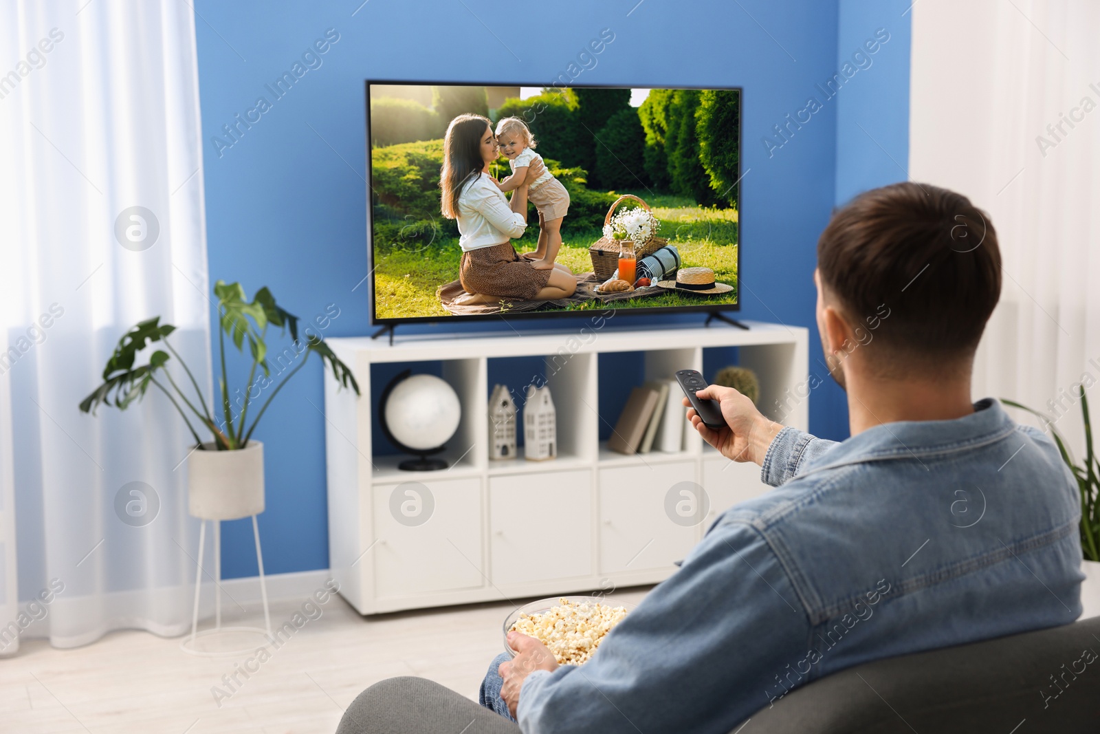 Image of Man watching movie on TV set at home