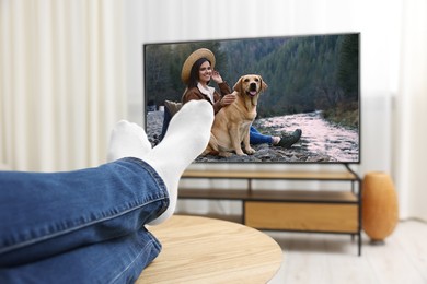 Image of Man watching movie on TV set at home