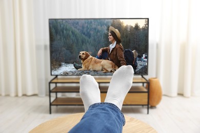 Image of Man watching movie on TV set at home