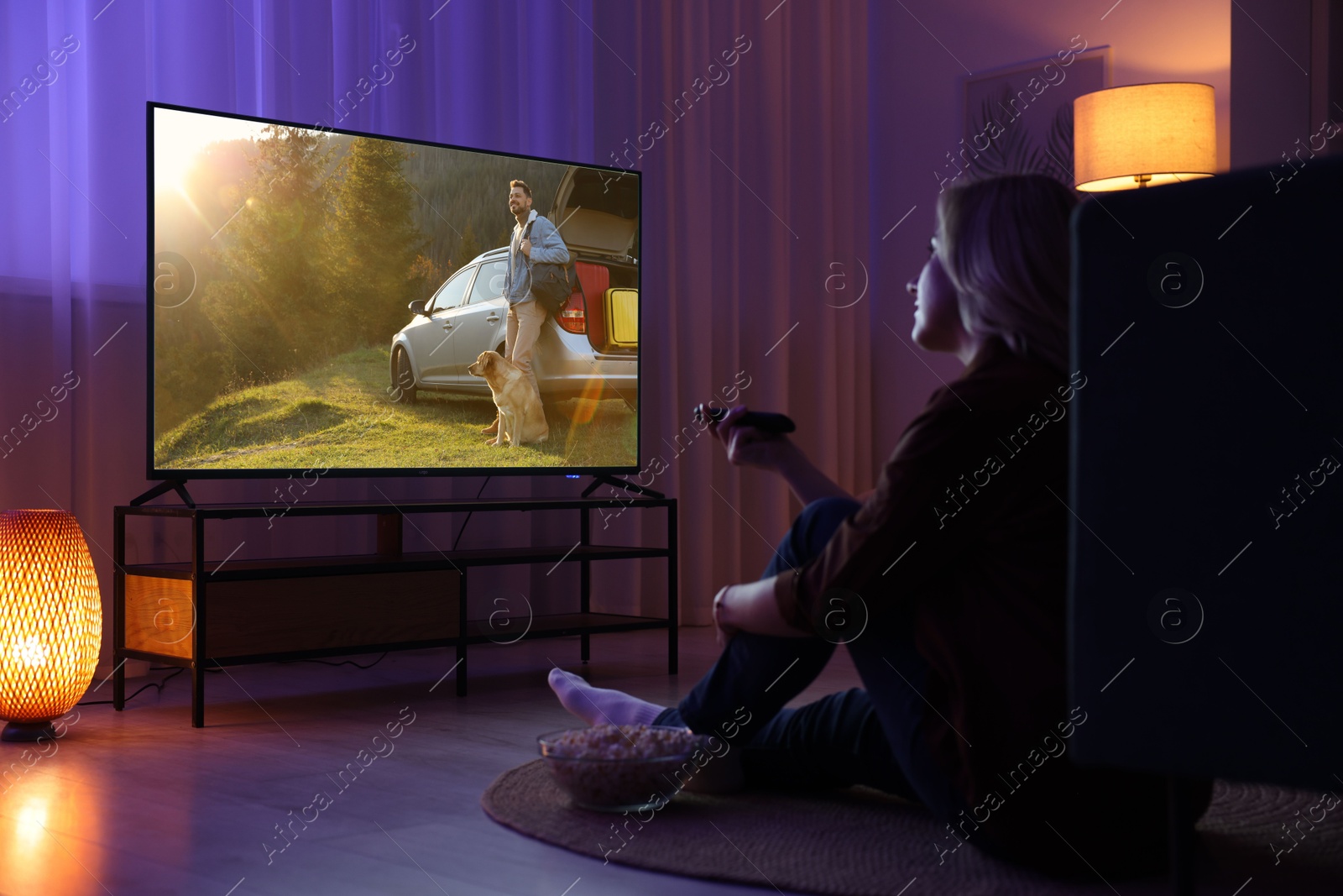 Image of Woman watching movie on TV set in room at night