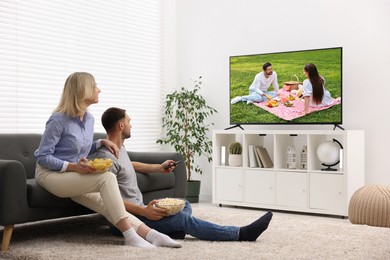 Image of Couple watching movie on TV set at home