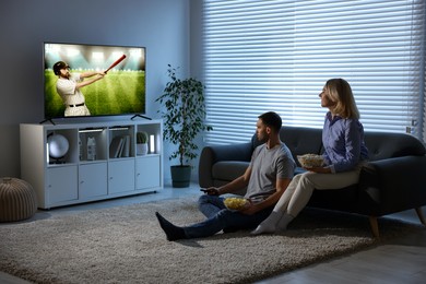 Image of Couple watching baseball game on TV set at home