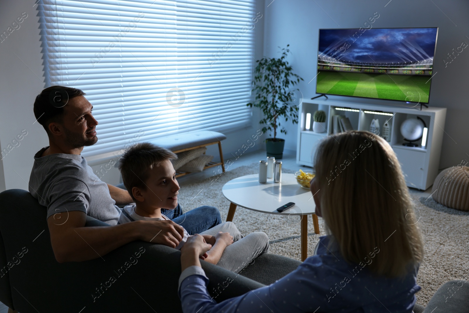 Image of Family watching sport game on TV set at home