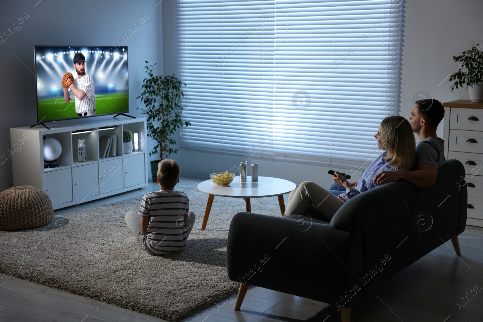 Image of Family watching baseball game on TV set at home