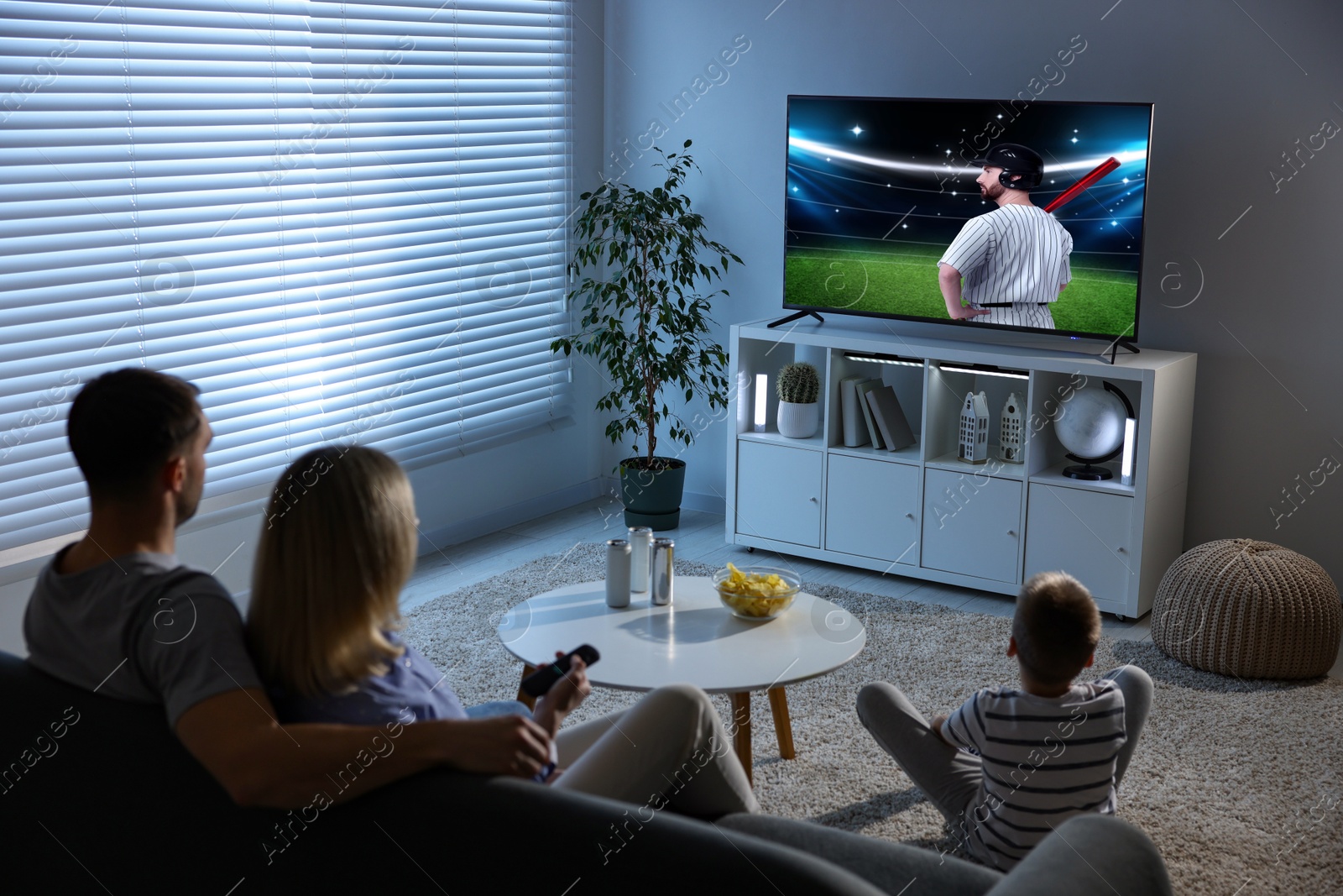 Image of Family watching baseball game on TV set at home