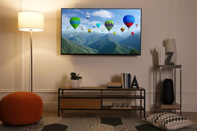 Image of TV set with hot air balloons floating over mountains on screen in room