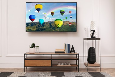 Image of TV set with hot air balloons floating over mountains on screen in room