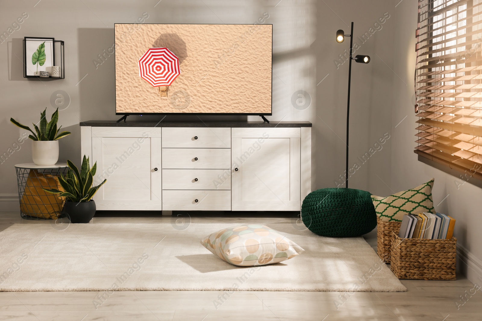 Image of TV set with umbrella amongst sandy beach on screen in room