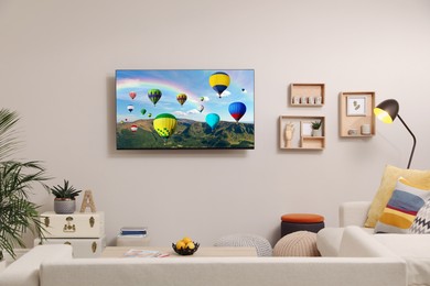 Image of TV set with hot air balloons floating over mountains on screen in room