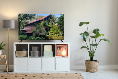 Image of TV set with beautiful house on screen in room