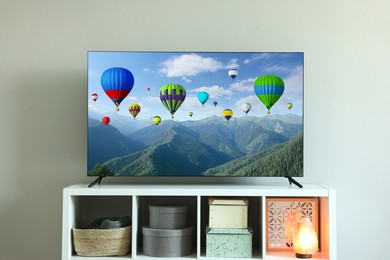 Image of TV set with hot air balloons floating over mountains on screen in room