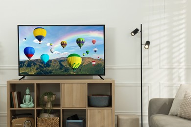 Image of TV set with hot air balloons floating over mountains on screen in room