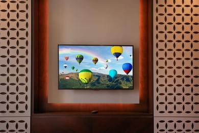 Image of TV set with hot air balloons floating over mountains on screen in room