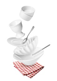 Image of Clean dishware and silverware flying over red checkered napkin on white background