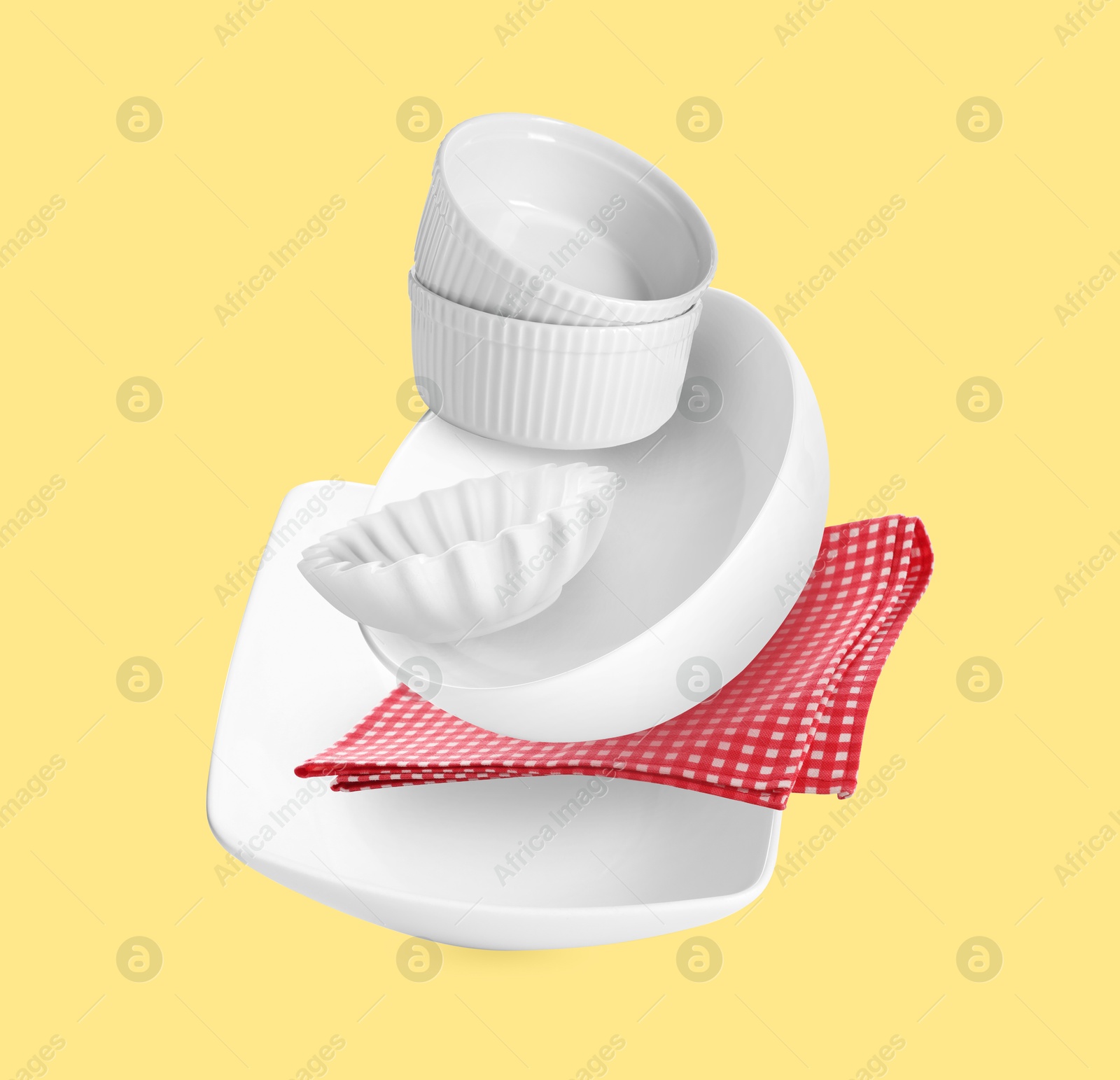 Image of Clean dishware and red checkered napkin flying on pastel yellow background