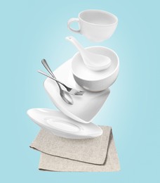 Clean dishware and silverware flying over napkin on light blue background