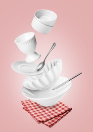 Image of Clean dishware and silverware flying over red checkered napkin on pink background