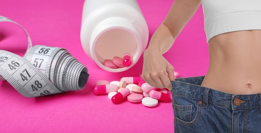 Image of Weight loss. Slim woman in big jeans, measuring tape and pills on pink background, closeup. Banner design