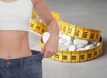 Image of Weight loss. Slim woman in big jeans, measuring tape and pills on grey background, closeup