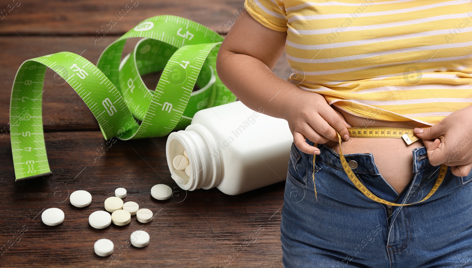 Image of Weight loss. Overweight woman measuring her waist with tape and pills, closeup. Banner design