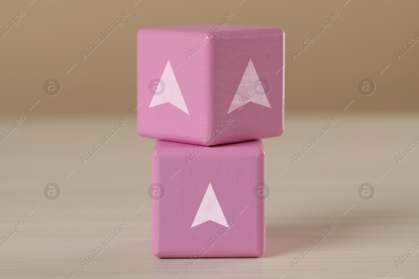 Image of Pink cubes with arrows on wooden table, closeup