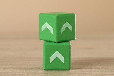 Image of Green cubes with arrows on wooden table, closeup