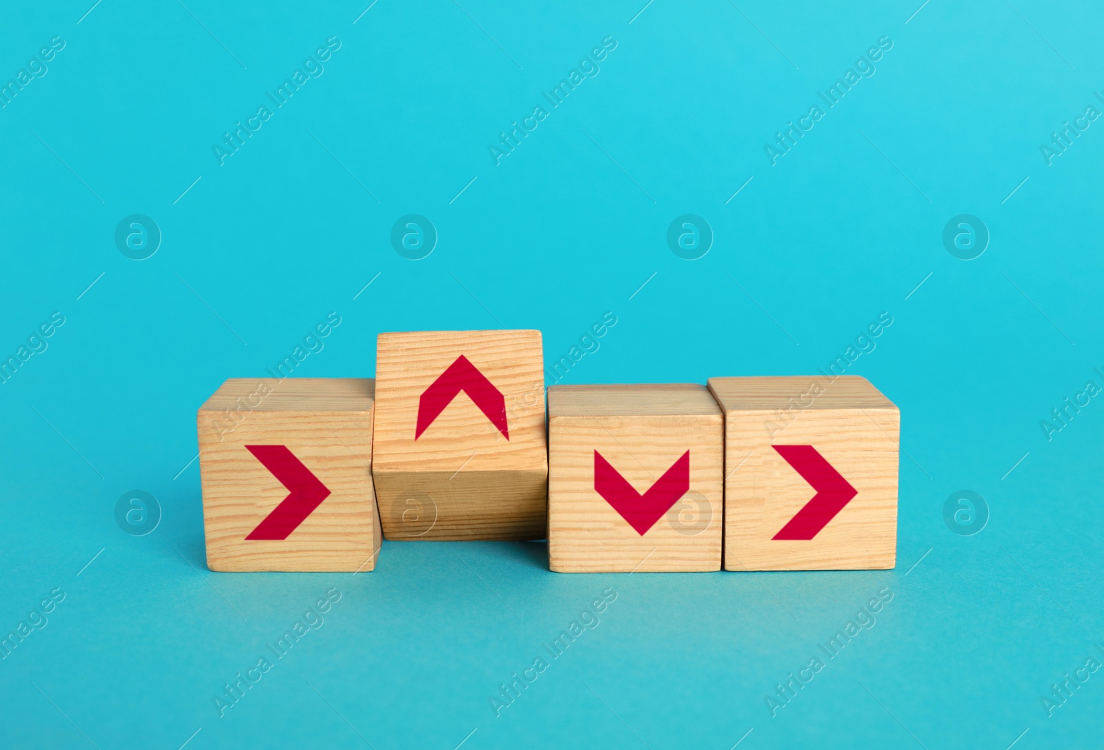 Image of Wooden cubes with arrows pointing in different directions on light blue background