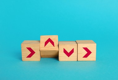 Image of Wooden cubes with arrows pointing in different directions on light blue background