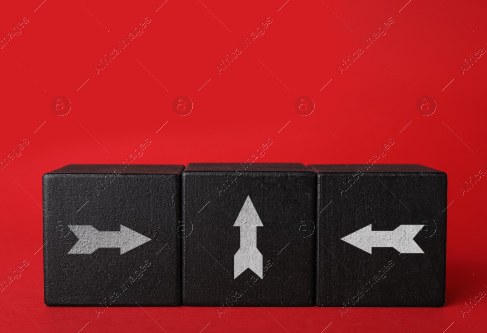 Image of Black cubes with white arrows pointing in different directions on red background