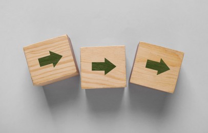 Image of Wooden cubes with green arrows on grey background, top view