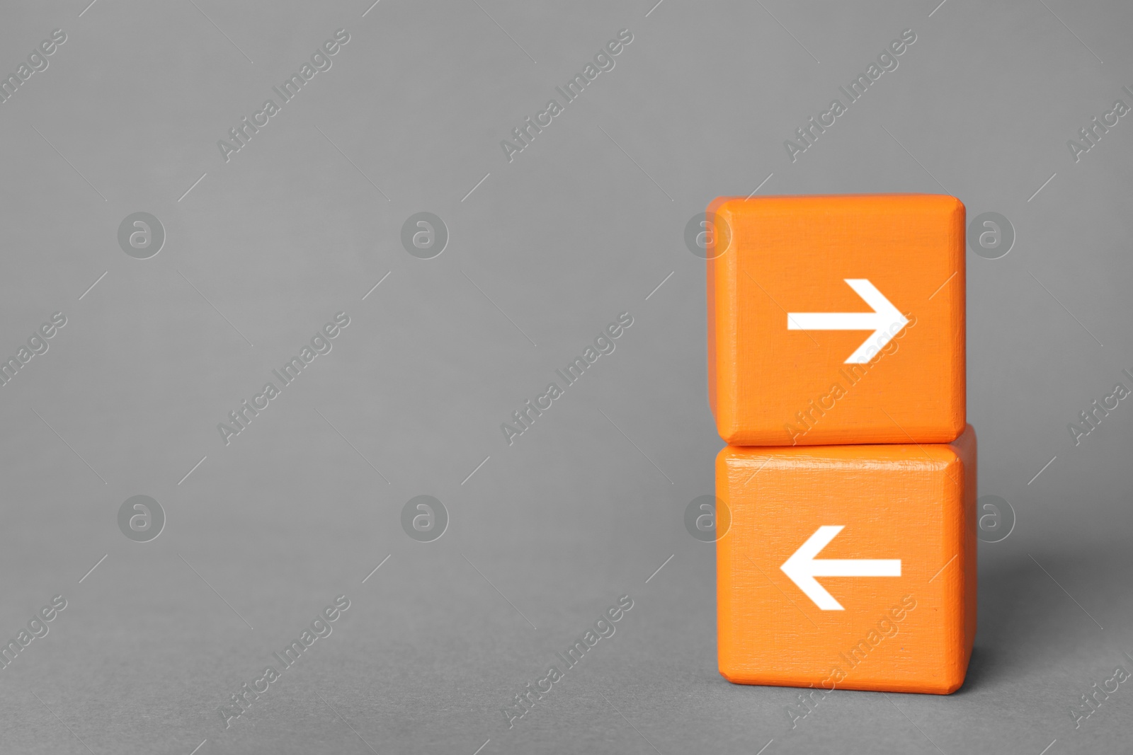 Image of Orange wooden cubes with arrows pointing in different directions on grey background, space for text