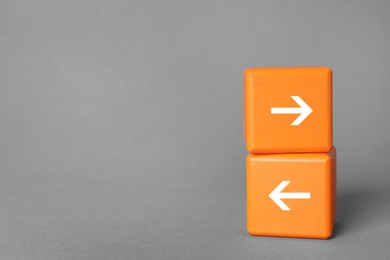 Image of Orange wooden cubes with arrows pointing in different directions on grey background, space for text