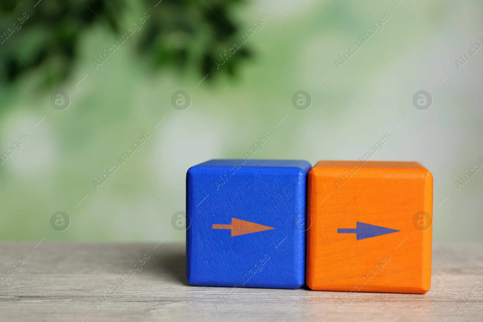 Image of Blue and orange cubes with arrows on wooden table