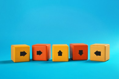 Image of Colorful cubes with arrows pointing in different directions on light blue background