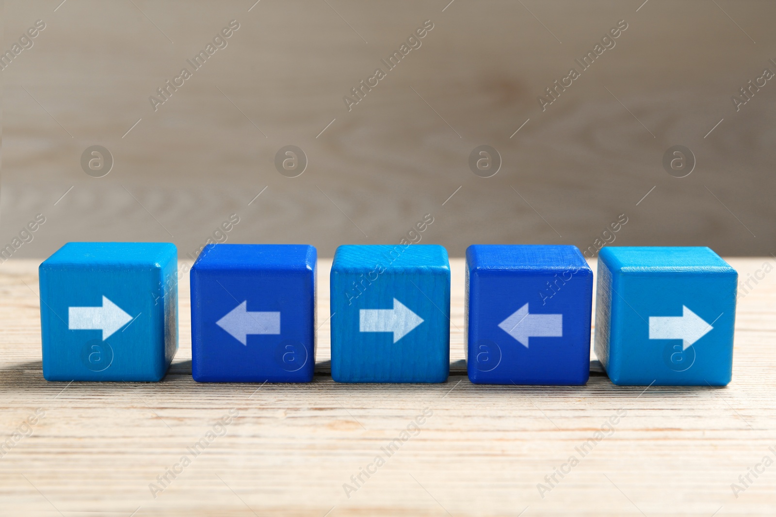 Image of Blue cubes with arrows pointing in different directions on wooden table