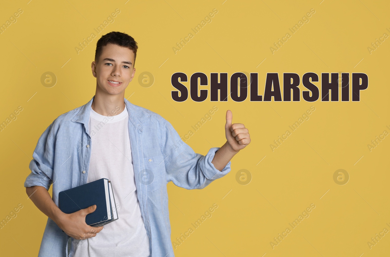 Image of Scholarship. Teenage boy with books showing thumbs up on yellow background