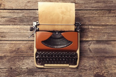 Image of Old vintage typewriter with paper on wooden table, top view