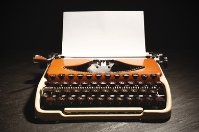 Image of Old vintage typewriter with paper on grey table against black background