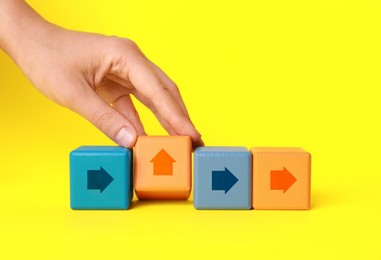 Image of Woman holding cube with arrow on yellow background, closeup