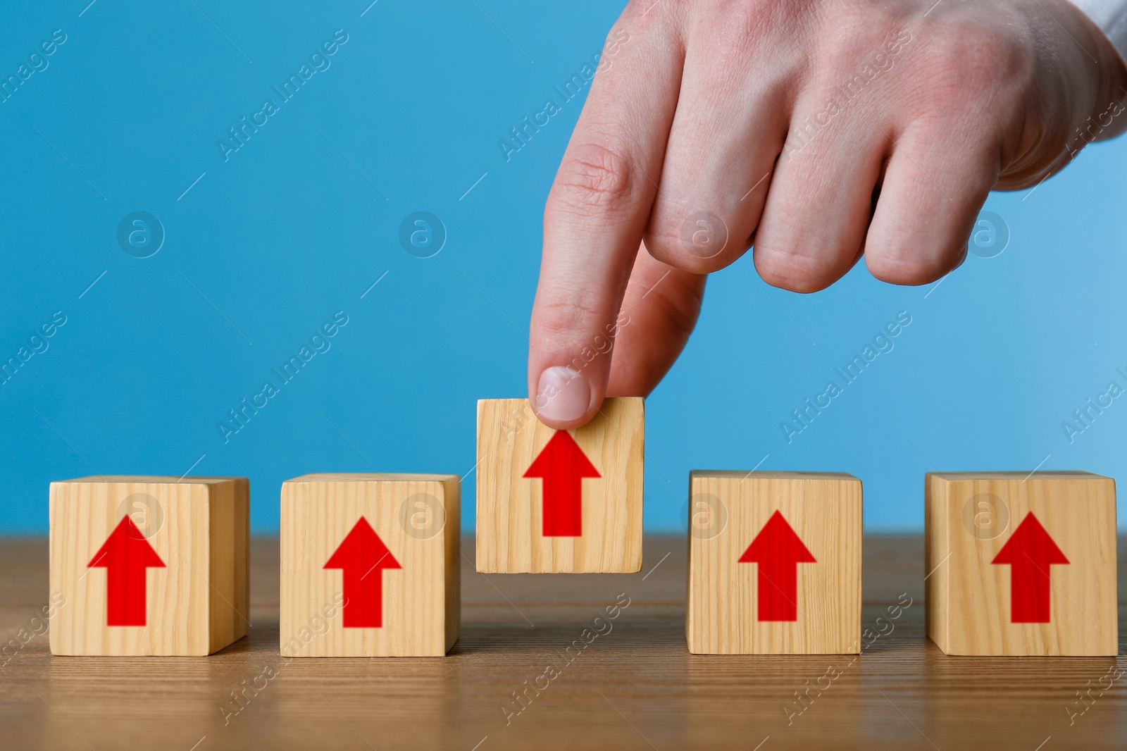 Image of Man holding cube with red arrow at wooden table, closeup