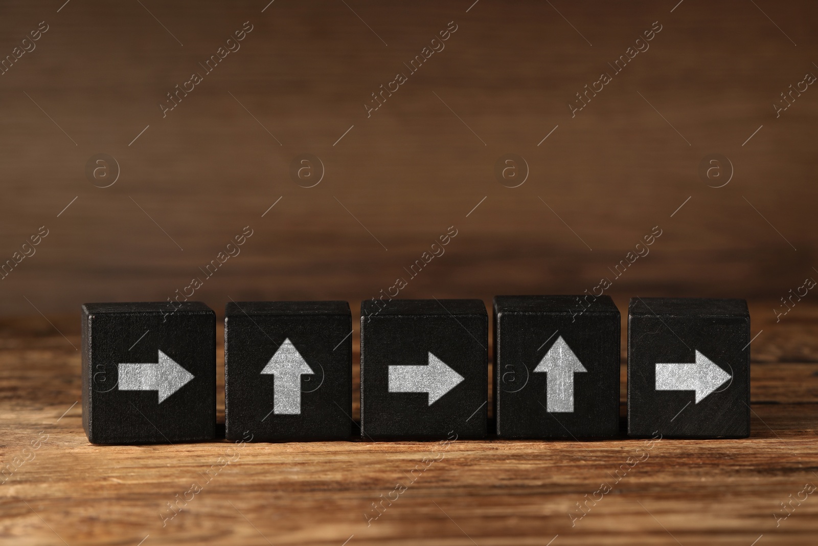 Image of Black cubes with white arrows on wooden table