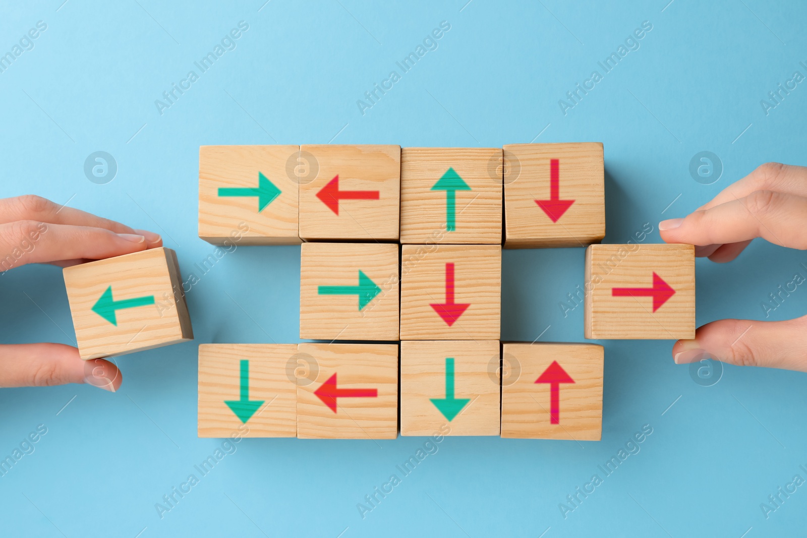 Image of People holding cubes with arrows on light blue background, top view