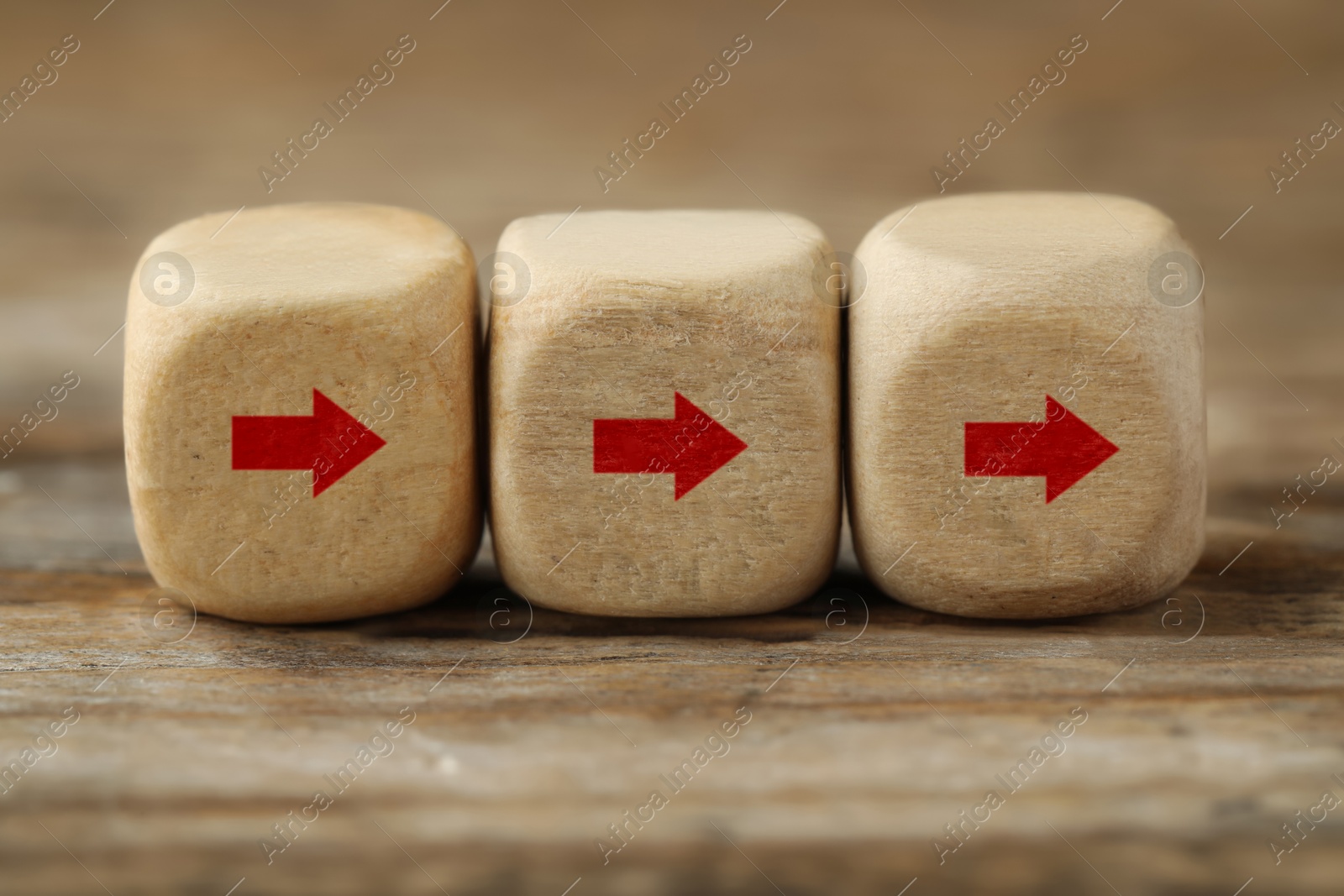 Image of Cubes with red arrows on wooden background, closeup