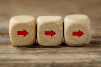 Image of Cubes with red arrows on wooden background, closeup