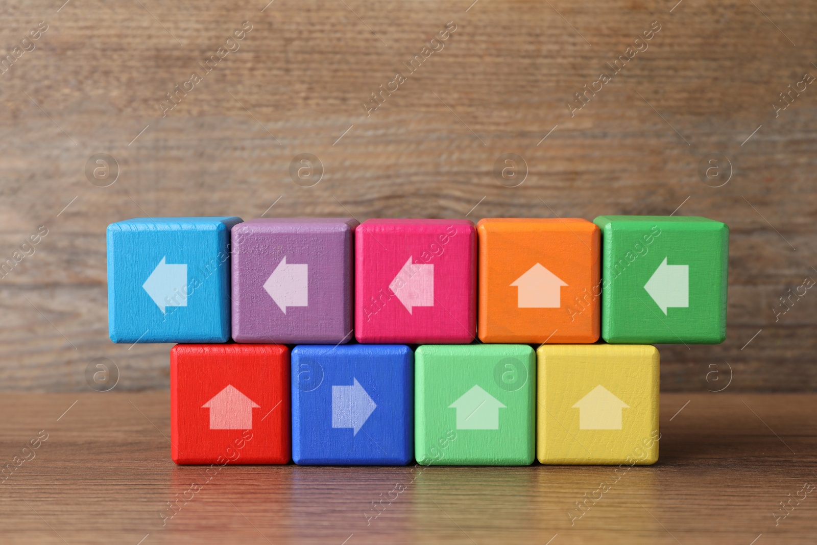 Image of Colorful cubes with arrows pointing in different directions on wooden table