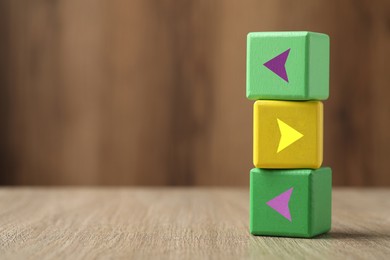 Image of Colorful cubes with arrows on wooden table, space for text