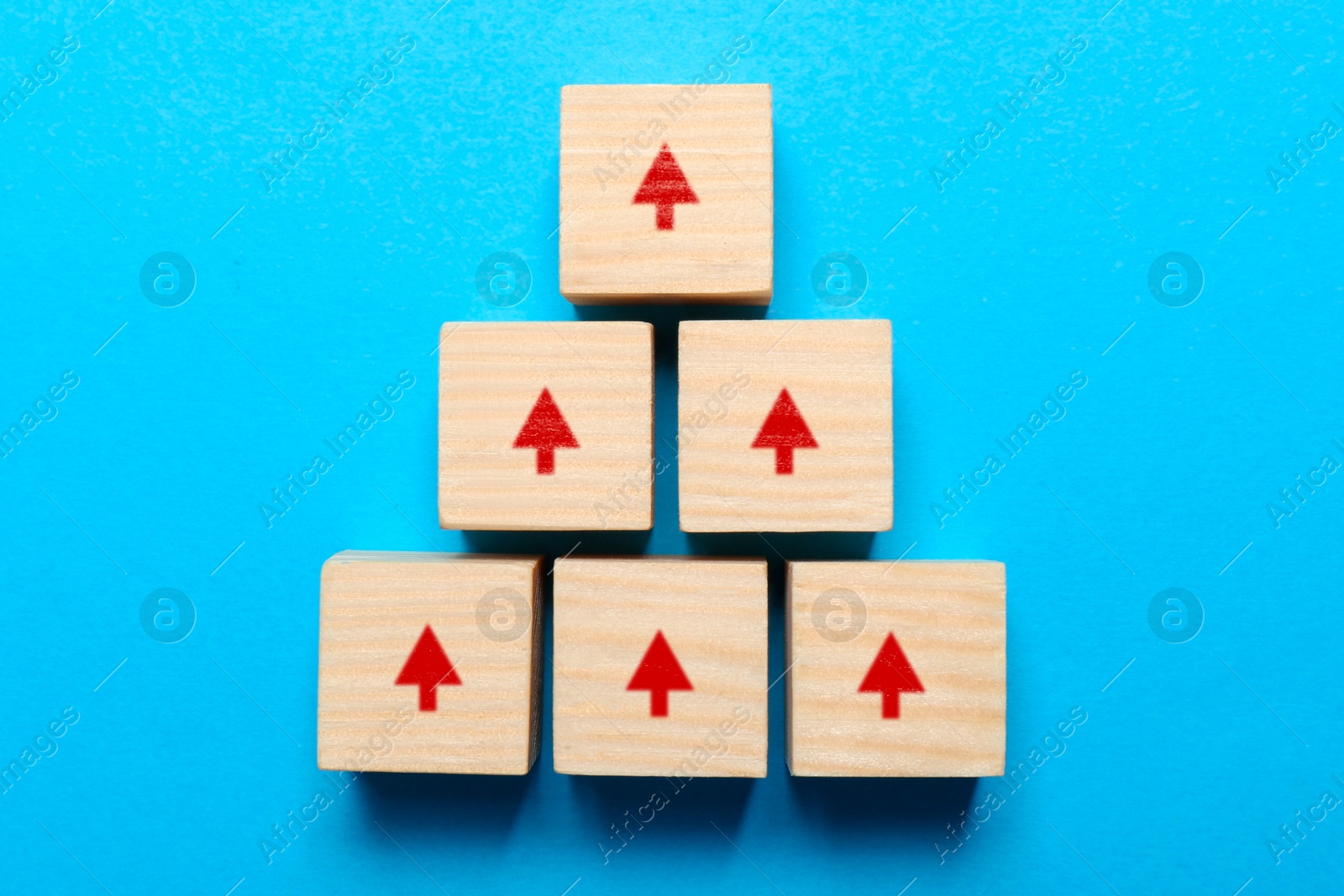 Image of Wooden cubes with red arrows on light blue background, top view