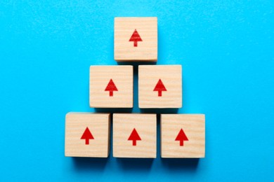 Image of Wooden cubes with red arrows on light blue background, top view