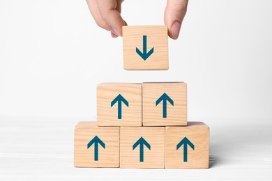 Image of Woman stacking wooden cubes with blue arrows on white background, closeup