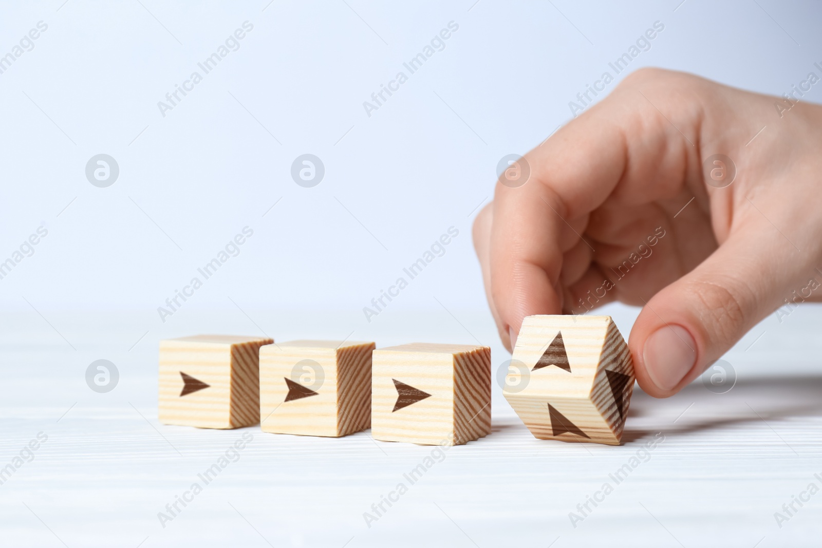 Image of Woman holding wooden cube with arrow on white background, closeup. Space for text